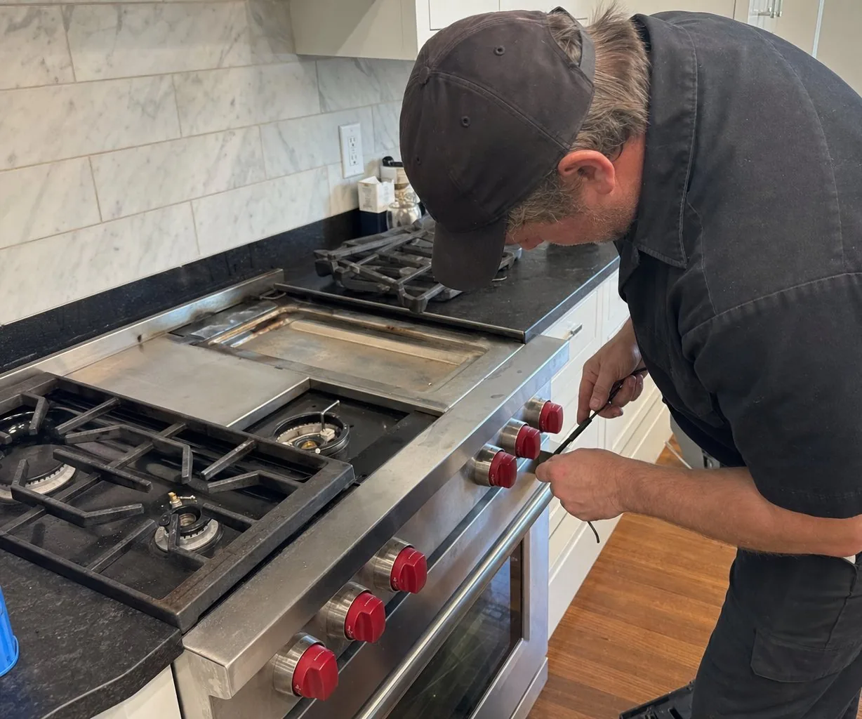 Technician servicing a stainless Wolf range in a Bedford kitchen